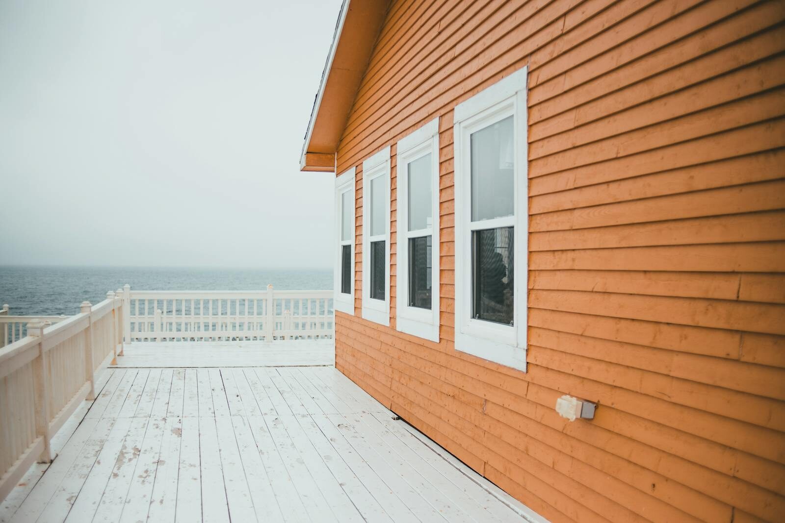 Decks & Exterior Projects Charming wooden house by the sea with ocean view and bright deck.